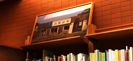 책방무사의 책장 위 한편에는 제주 수산리 시절 책방의 모습이 담겨 있는 액자가 놓여 있다.
