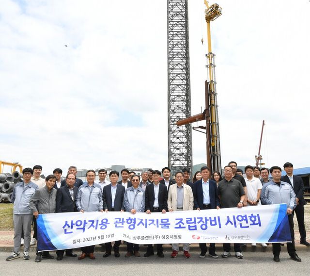 시연회 참석자들이 산악지용 관형지지물 조립장비 앞에서 포즈를 취하고 있다. [사진=한전전력연구원]