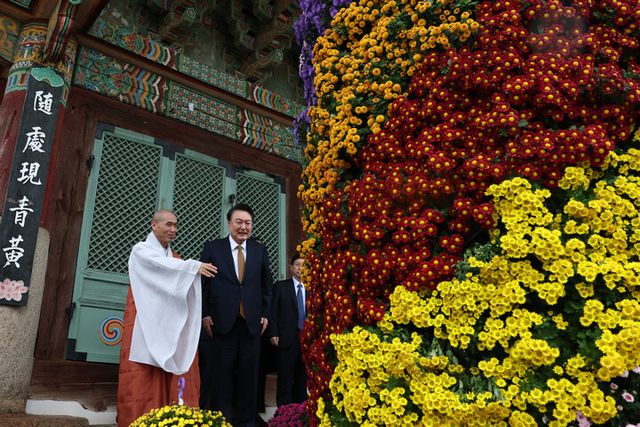 윤석열 대통령이 22일 부산 금정구 범어사를 찾아 대웅전 입구 양쪽에 장식된 국화를 바라보며 주지 정오스님과 대화하고 있다. [사진=대통령실]