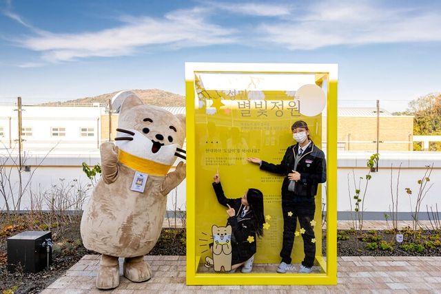 창원성민여고 학생들이 경상남도 창원특례시 의창구에 위치한 창원성민여고에서 현대위아의 캐릭터 ‘도담이’와 함께 기념사진을 찍고 있다. [사진=현대위아]