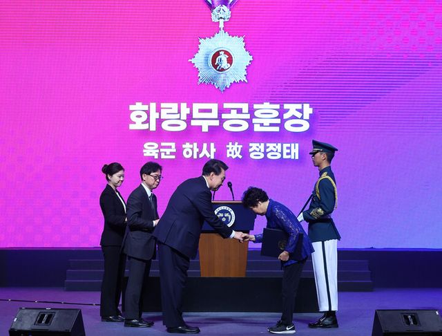 윤석열 대통령이 25일 대구 엑스코에서 열린 '6·25전쟁 제74주년 행사'에서 1사단 15연대 소속 고(故) 정정태 하사의 동생 정정순 씨에게 화랑무공훈장을 수여하고 있다. [사진=연합뉴스]