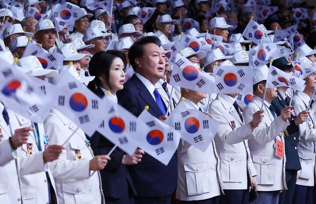 윤석열 대통령과 김건희 여사가 25일 오전 대구 엑스코에서 열린 '6·25전쟁 제74주년 행사'에서 6·25의 노래를 부르며 태극기를 흔들고 있다. [사진=연합뉴스]