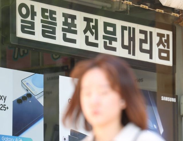 한 시민이 서울의 한 알뜰폰 매장 앞을 지나가고 있다. [사진=연합뉴스]