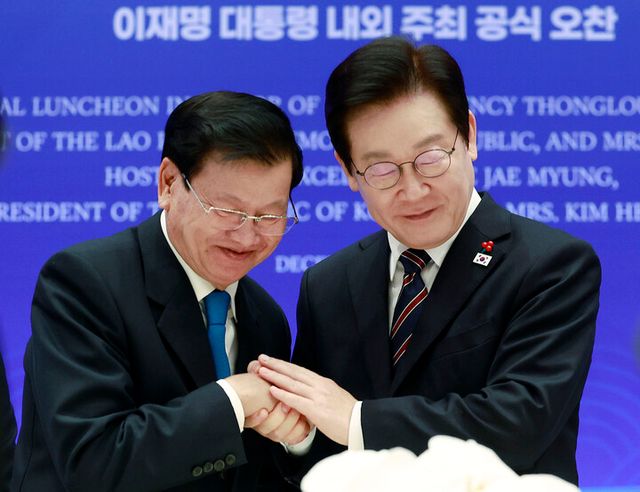이재명 대통령이 15일 용산 대통령실에서 열린 한-라오스 공식오찬에서 통룬 시술릿 라오스 국가주석과 건배 후 손을 맞잡고 있다. [사진=연합뉴스]
