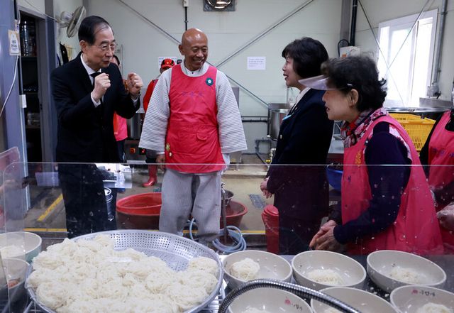 한덕수 대통령 권한대행 국무총리가 28일 국립대전현충원 내 구암사 나눔의 집 '나마스테'를 방문해 두손을 불끈쥐며 국수나눔 자원봉사자들을 격려하고 있다. [사진=연합뉴스]