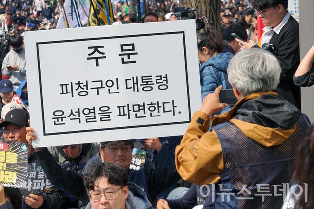 &nbsp;윤석열 대통령의 탄핵심판 청구가 인용된 4일 오전 서울 종로구 헌법재판소 인근에서 진행된 탄핵 찬성 집회에 참가한 한 시민이 탄핵을 촉구하는 플랭카드를 들고 있다. [사진=안경선 기자]