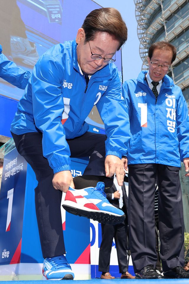 이재명 더불어민주당 대선 후보가 6·3 대통령선거 공식 선거운동 첫날인 12일 서울 광화문 청계광장에서 열린 중앙선대위 출정식 및 첫 유세에서 구두를 벗고 운동화로 갈아신고 있다. [사진=연합뉴스]