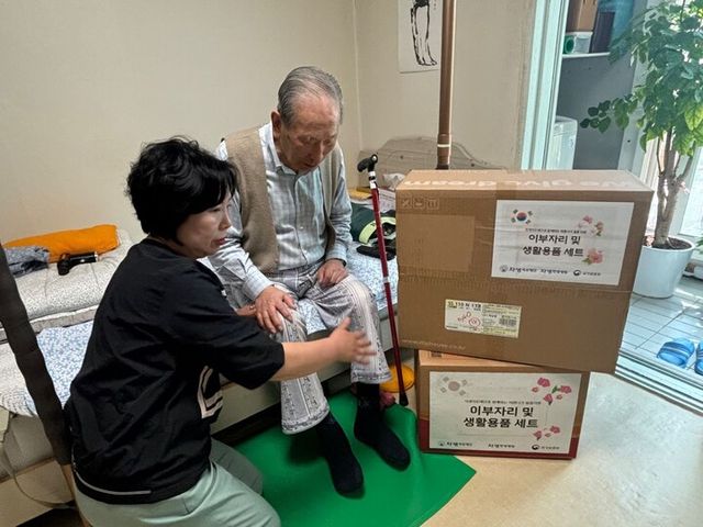 자생의료재단 관계자가 독립유공자 어르신 가정을 방문해 여름 침구류 세트와 생필품을 전달하고 있다. [사진=자생한방병원]