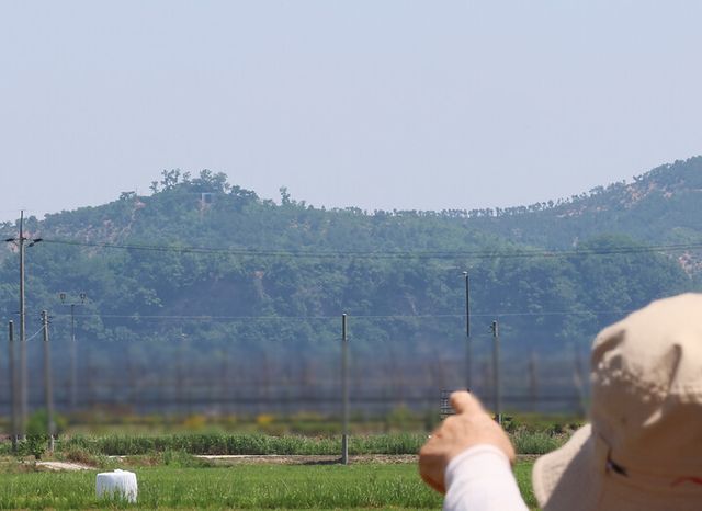 북한이 우리 군의 대북 확성기 방송 중지에 호응해 대남 소음 방송을 멈춘 것으로 보이는 12일 인천 강화군 송해면 당산리 주민들이 북한 개풍군 야산에 설치된 북한 대남 방송 스피커를 가르키고 있다. [사진=연합뉴스]