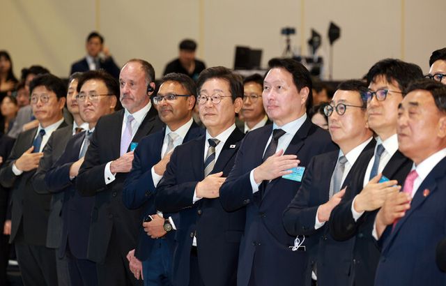 이재명 대통령이 20일 울산전시컨벤션센터에서 열린 울산 인공지능(AI) 데이터센터 출범식에서 국기에 경례하고 있다. 이 대통령 오른쪽은 최태원 SK그룹 회장. [사진=연합뉴스]