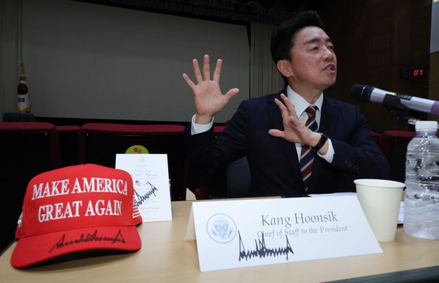 강훈식 비서실장이 28일 용산 대통령실에서 기자간담회 중 트럼프 대통령에게 본인이 받은 선물에 대해 설명하고 있다. 그 앞에 트럼프 대통령의 사인이 있는 마가 모자, 오찬 메뉴판, 비서실장 명패 등이 놓여 있다. [사진=연합뉴스]