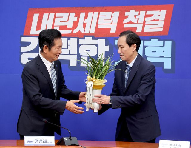 정청래 더불어민주당 신임 대표가 4일 국회 당대표실을 예방한 우상호 대통령실 정무수석으로부터 이재명 대통령의 취임 축하 난을 전달받고 있다. [사진=연합뉴스]