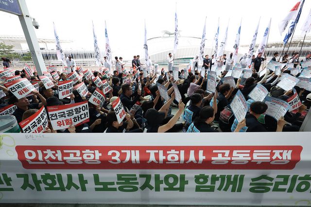 인천국제공항 노동자가 가입한 민주노총 공공운수노조 인천공항지역지부와 나머지 14개 공항 노동자가 가입한 전국공항노동조합으로 구성된 전국공항노동자연대가 19일 인천 영종도 인천국제공항 제2여객터미널에서 연 총파업 대회에서 참가자들이 손팻말을 들고 구호를 외치고 있다. 전국공항노동자연대는 이날 경고 파업을 진행한 후 추석 연휴 전 무기한 총파업을 진행할 것이라고 예고했다. [사진=연합뉴스]