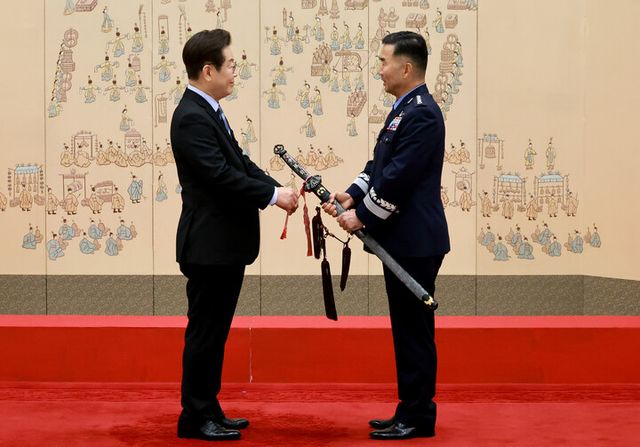 이재명 대통령이 2일 서울 용산 대통령실 청사에서 열린 대장 진급·보직 신고식에서 합동참모의장 후보자인 진영승 공군 전략사령관에게 삼정검 수치를 달아주고 있다. [사진=연합뉴스]