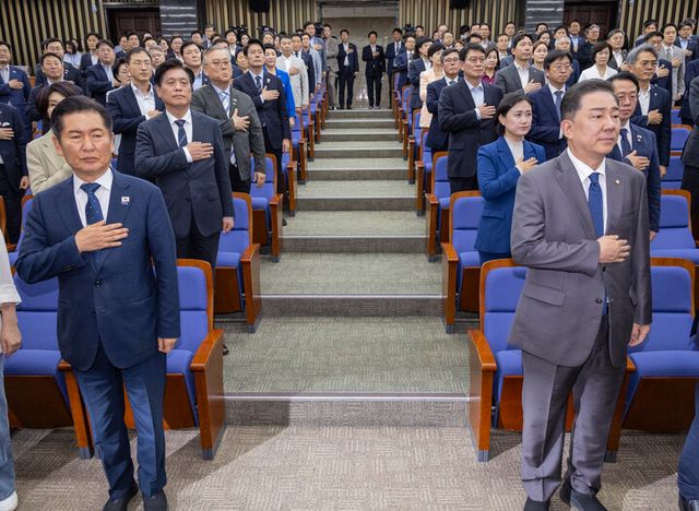 정청래 대표와 김병기 원내대표를 비롯한 더불어민주당 소속 의원들이 3일 국회에서 열린 검찰개혁ㆍ정부조직법 개편 의견 수렴을 위해 열린 정책 의원총회에 참석해 국기에 경례하고 있다. [사진=연합뉴스]