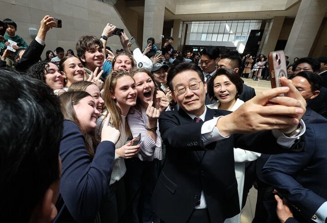 이재명 대통령과 김혜경 여사가 26일 서울 용산구 국립중앙박물관에서 열린 특별전 '우리들의 이순신' 관람을 마친 뒤 외국인 관람객과 기념촬영을 하고 있다. [사진=연합뉴스]