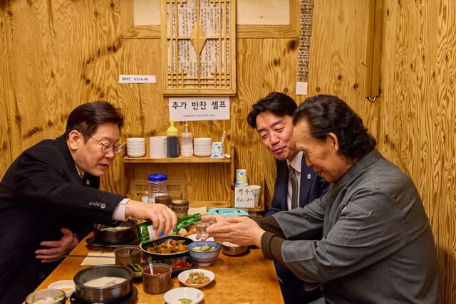 이재명 대통령이 9일 서울 종로구 통인시장 한식당에서 강훈식 대통령비서실장과 저녁 식사를 하며 식당 주인에게 술을 권하고 있다. [사진=청와대]