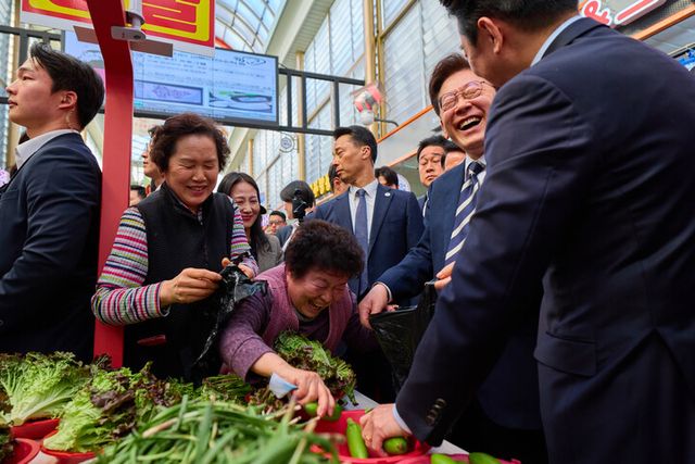 이재명 대통령이 25일 한국항공우주산업(KAI)에서 열린 KF-21 양산 1호기 출고식에 참석한 뒤 경남 진주시 진주중앙시장을 방문해 상인과 대화를 나누고 있다. [사진=청와대]