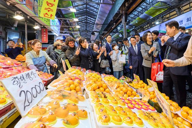 이재명 대통령이 30일 제주 타운홀미팅을 마친 뒤 김혜경 여사와 함께 제주시 동문시장을 찾아 과일을 구매하고 있다. [사진=연합뉴스]