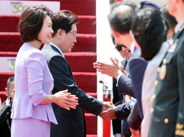 인도 국빈방문을 마친 이재명 대통령과 김혜경 여사가 21일(현지 시각) 다음 국빈 방문지인 베트남으로 가기 위해 뉴델리 팔람 공군기지에서 공군 1호기에 탑승 전 환송객과 인사하고 있다. [사진=연합뉴스]