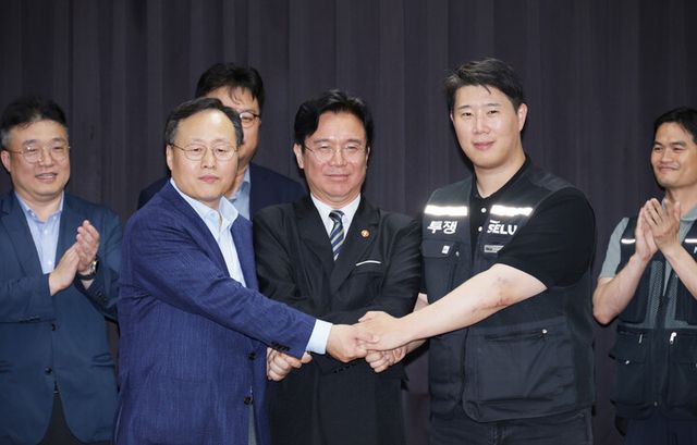 20일 경기도 수원시 장안구 경기고용노동청에서 열린 삼성전자 임금협상을 마친 후 여명구 삼성전자 DS(디바이스솔루션·반도체 사업 담당) 피플팀장과 최승호 삼성그룹 초기업노동조합 삼성전자지부 위원장이 잠정 합의안에 서명한 후 김영훈 고용노동부 장관과 손을 맞잡고 있다. [사진=연합뉴스]