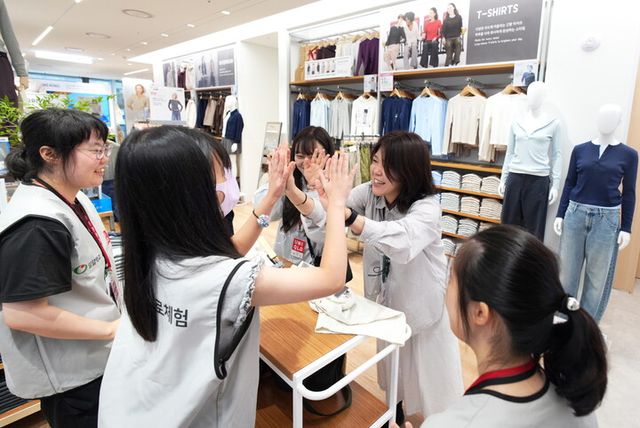 직업 역량 향상 및 진로 체험 프로그램의 일환으로 의류 정리 및 상품 진열 실습에 참여한 밀알학교 학생과 학생들을 응원하는 유니클로 직원. [사진=유니클로]