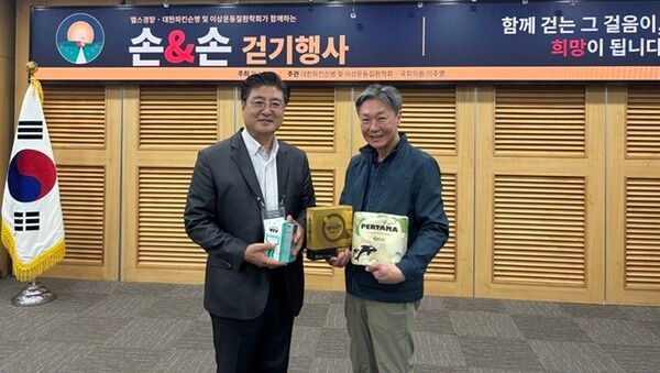 이번 행사에는 여러 기업이 후원에 동참해 파킨슨병환자와 가족들의 건강한 일상을 응원했다. 헬스경향 조창연 대표(오른쪽)는 환자 대표에게 후원기업이 마련한 기념품을 전달했다.
