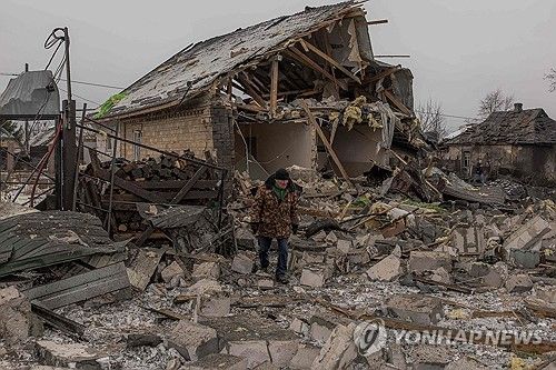 폭격맞은 집 앞을 지나는 우크라이나 주민