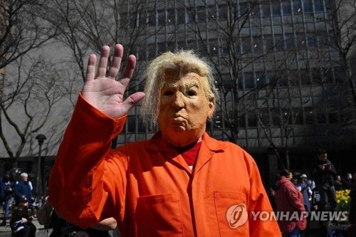 죄수복 차림으로 트럼프 전 대통령의 가면을 쓴 미국 시민