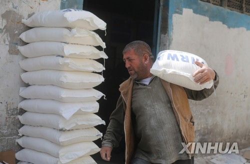 유엔 팔레스타인 난민구호기구가 제공한 밀가루 포대를 옮기는 가자지구 주민.