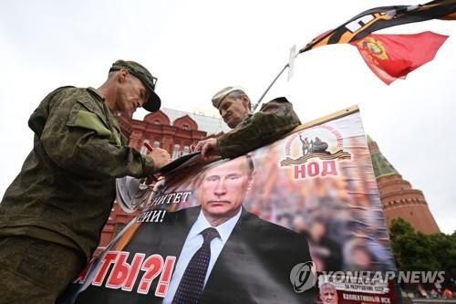 (모스크바 AFP=연합뉴스) 24일(현지시간) 러시아 모스크바 붉은 광장 근처에서 푸틴 대통령 지지자들이 그의 포스터를 들고 있는 모습. 2023.06.24