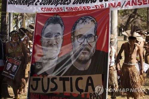 작년 아마존 열대우림에서 살해당한 브라질인 원주민 전문가 부루노 페레이라와 영국 언론인 돔 필립스의 사진을 들고 행진하는 아마존 원주민들. [EPA=연합뉴스자료사진. 재판매 및 DB 금지]