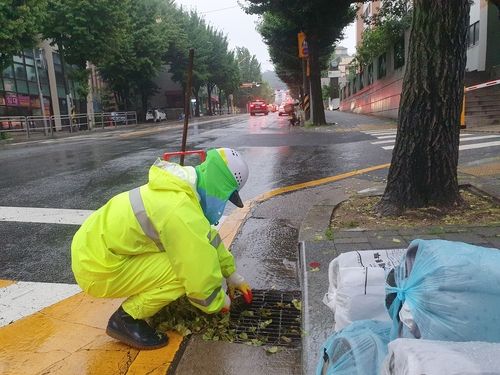지난 14일 오전 6시 환경미화원 정한준씨가 쪼그려 앉아 빗물받이를 청소하고 있다