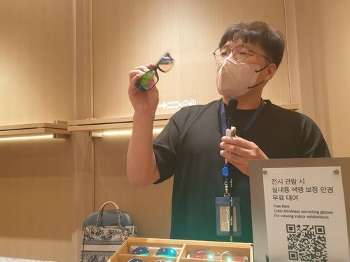 (용인=연합뉴스) 황희경 기자 = 경기 용인의 호암미술관 관계자가 전시 관람 때 쓸 수 있는 실내용 색맹 보정 안경에 대해 설명하는 모습. 2023.7.23. zitrone@yna.co.kr