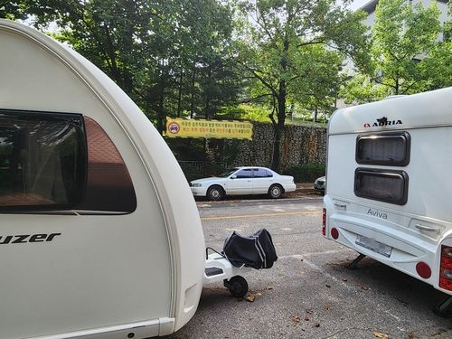 캠핑카 사이로 보이는 캠핑카 주차 금지 현수막