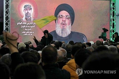 헤즈볼라 지도자 하산 나스랄라의 TV 연설이 진행되는 가운데, 한 남성이 헤즈볼라 깃발을 흔들고 있다. 