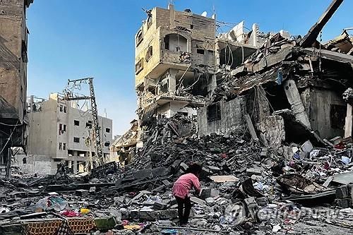 이스라엘 공습으로 무너진 건물 잔해 더미를 뒤적이는 팔레스타인 소녀