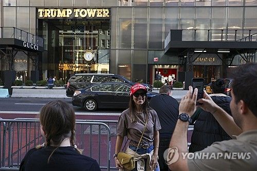 뉴욕 트럼프 타워 앞에서 'MAGA' 모자를 쓰고 사진을 찍는 관광객