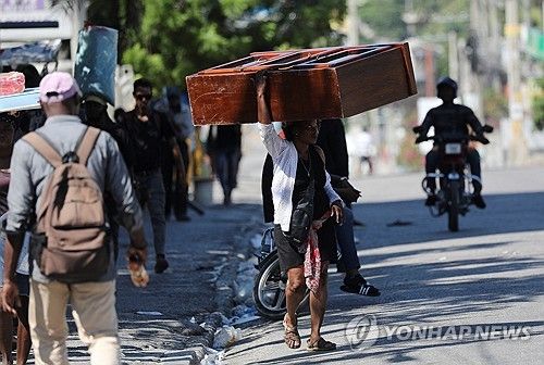 19일(현지시간) 머리에 가구를 이고 이동하는 아이티 주민
