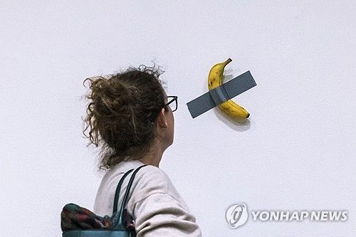 소더비 경매 전 전시된 마우리치오 카텔란의 작품 '코미디언'을 살펴보는 관람객