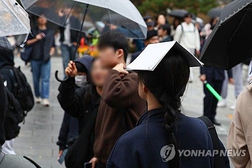 16일 오후 2025학년도 대입 수시모집 논술시험이 열린 서울 종로구 성균관대학교에서 시험을 마친 한 수험생이 종이로 비를 피하고 있다. [연합뉴스 자료사진]