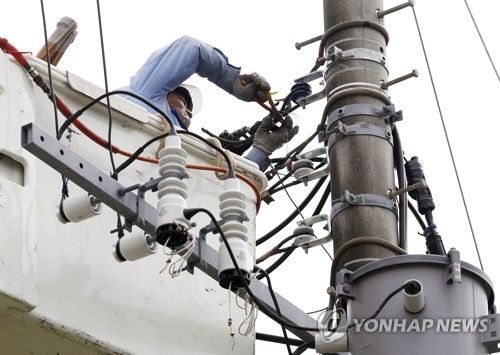 전신주에 올라 전선 보수 작업하는 한 작업자