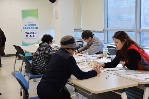 내년 노인 일자리 사업에 참여하기 위해 신청서를 작성하는 노인들