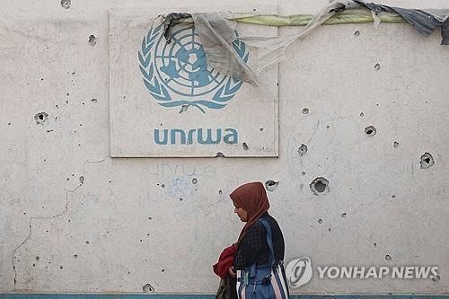 총탄 자국이 가득한 요르단강 서안 대피소 벽면에 부착된 팔 난민구호기구 로고