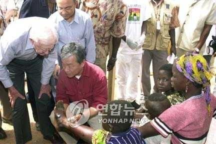 [지미 카터(왼쪽) 전 미국 대통령이 2004년 2월 이종욱(가운데) 당시 세계보건기구(WHO) 사무총장과 함께 아프리카 가나의 농촌을 방문해 기생충 퇴치사업 실태를 살펴보는 모습.A. POYO 제공. 재판매 및 DB 금지]