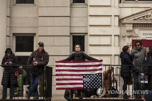 거꾸로 된 성조기를 들고 있는 시위자 