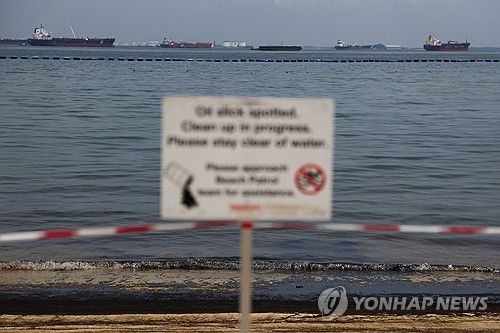 기름띠가 밀려온 해변 멀리 보이는 유조선들