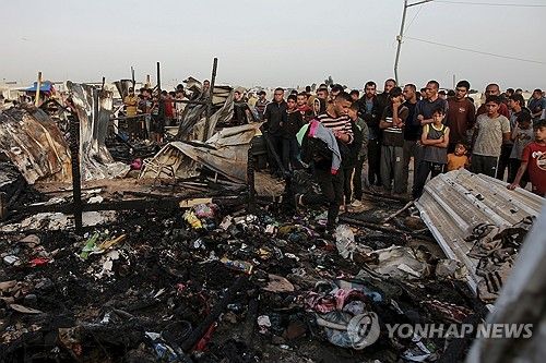 이스라엘의 폭격으로 잿더미가 된 임시거주지 주변에 둘러선 피란민들