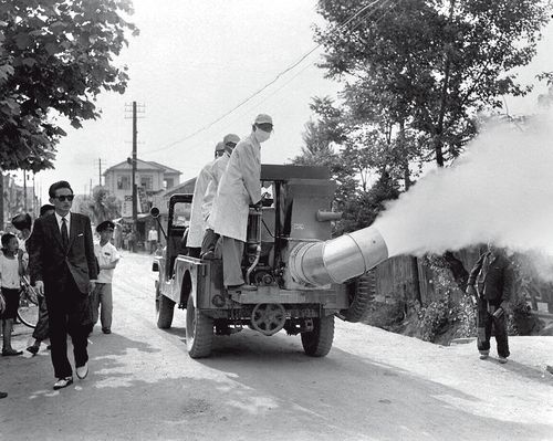 전염병을 옮기는 모기와 파리 등 해충을 없애려고 흰 연기를 내뿜으며 시내 곳곳을 달리는 소독차를 사람들이 신기하게 바라보고 있다. 1960년 [국가기록원 제공]