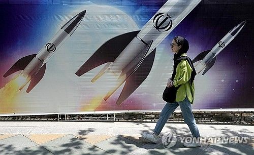미사일이 그려진 벽화 앞을 지나는 테헤란 시민
